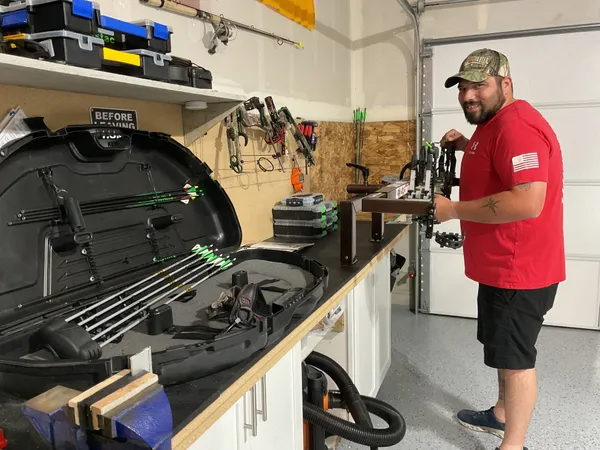 Technician inspecting a compound bow on the shop workbench